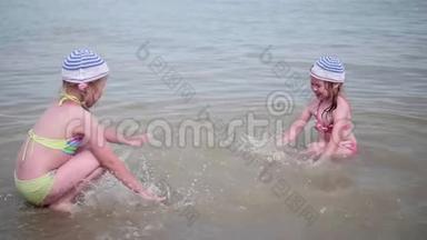 两个女孩在海滩上泼水。 在炎热的夏日里，双胞胎倒着水，<strong>孩子</strong>们的<strong>笑声</strong>和好心情